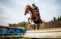 Pavel Kašný skáče před překážku na koni