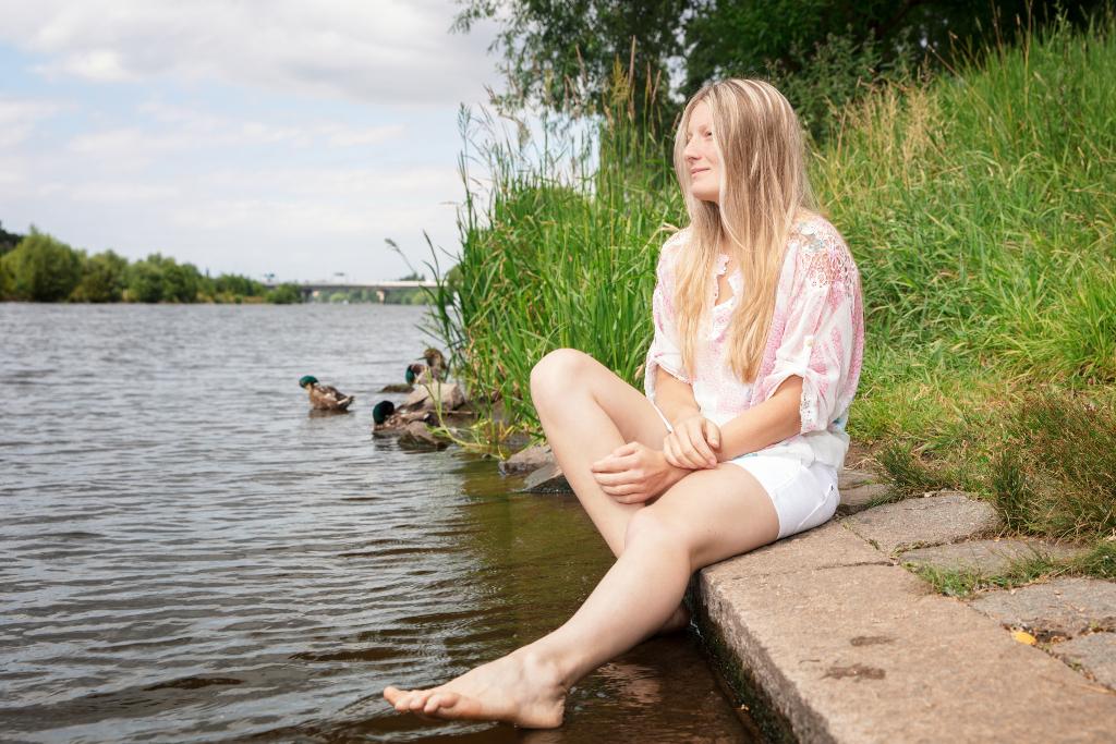 Nikola Hájková sedí u vody, má za sebou kačery