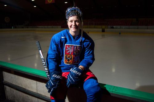 Alena Polenská sedí na mantinelu a dívá se do kamery, lední hokej