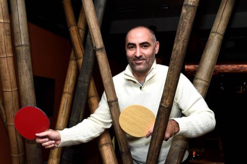 Petr Korbel stojí mezi bambusovými tyčemi s pálkami stolního tenisu