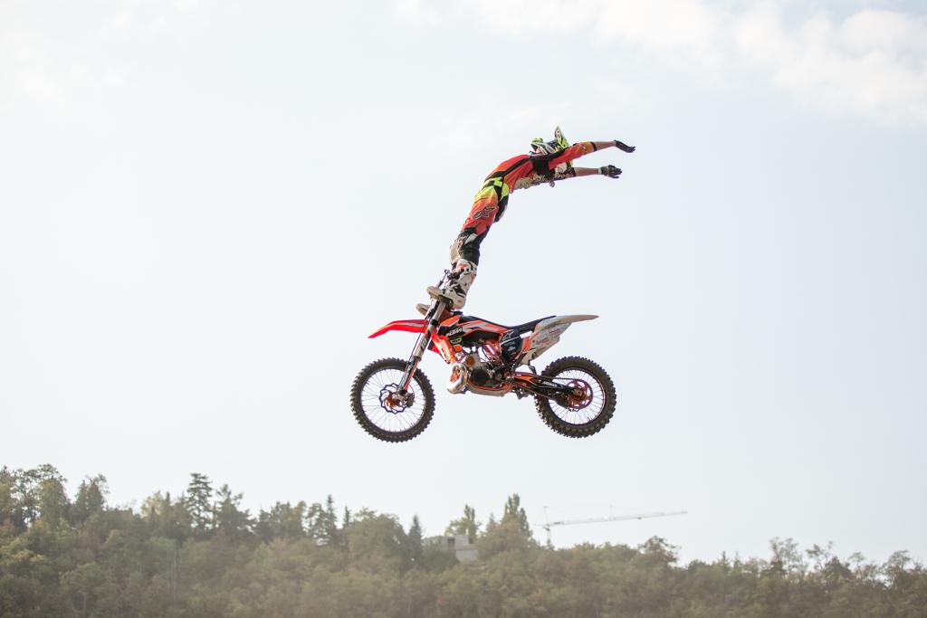 Petr Pilát při skoku s motorkou, kde na ní stojí v letu
