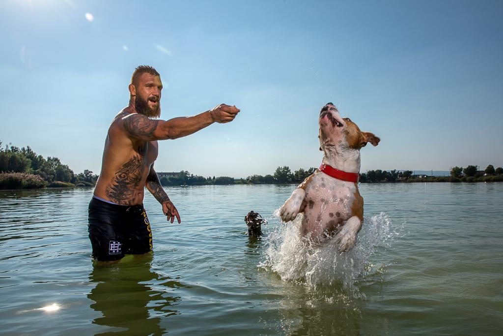 Samuel Krištofič si hraje se psy ve vodě, na těle má tetování 