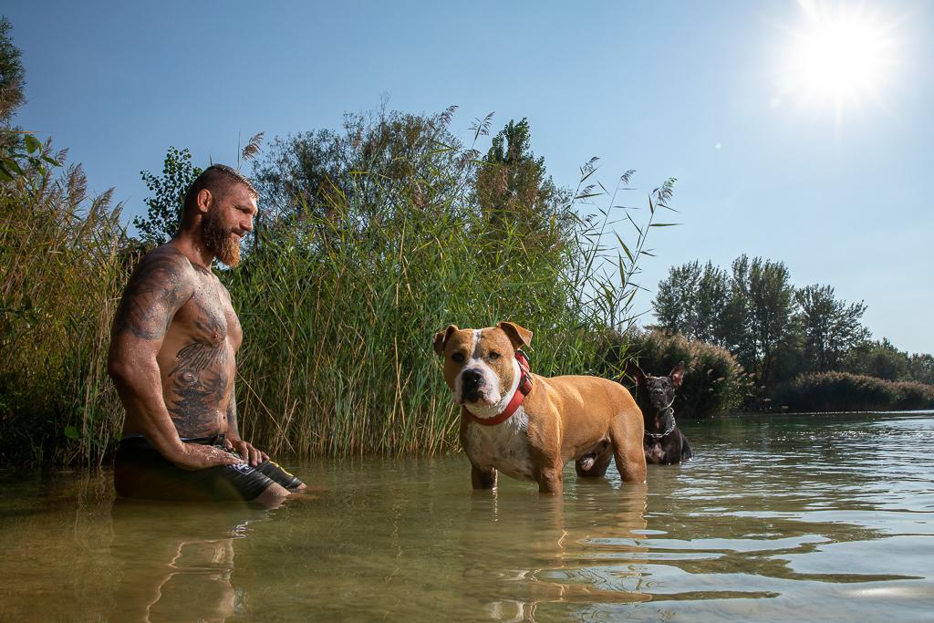Samuel Krištofič je ve vodě v přírodě se psy, má na sobě tetování 