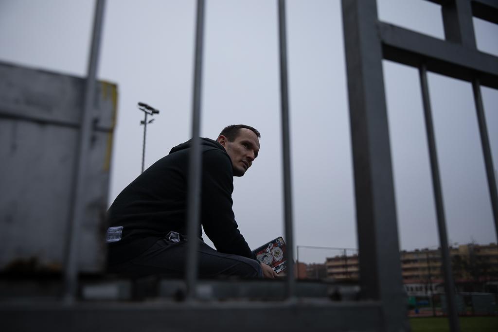 Ondřej Kašpárek sedí za zábradlím na fotbalovém stadionu, v ruce má zápisník