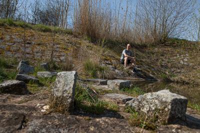 Tomáš Řenč sedí na kamenech u vody v přírodě
