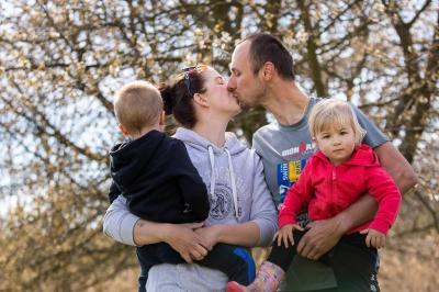 Tomáš Řenč si dává pusu s manželkou, oba drží děti, v přírodě