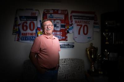 Vladimír Martinec před zdí, na které visí dresy HC Pardubice Martinec 60, 43, 70, na poličce jsou poháry a trofeje