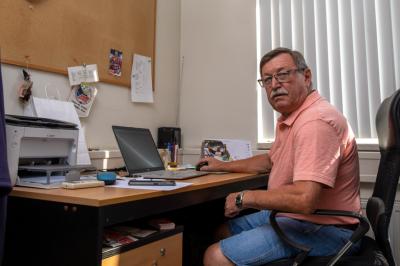 Vladimír Martinec sedí v kanceláři u stolu s notebookem, tiskárnou a kalendářem