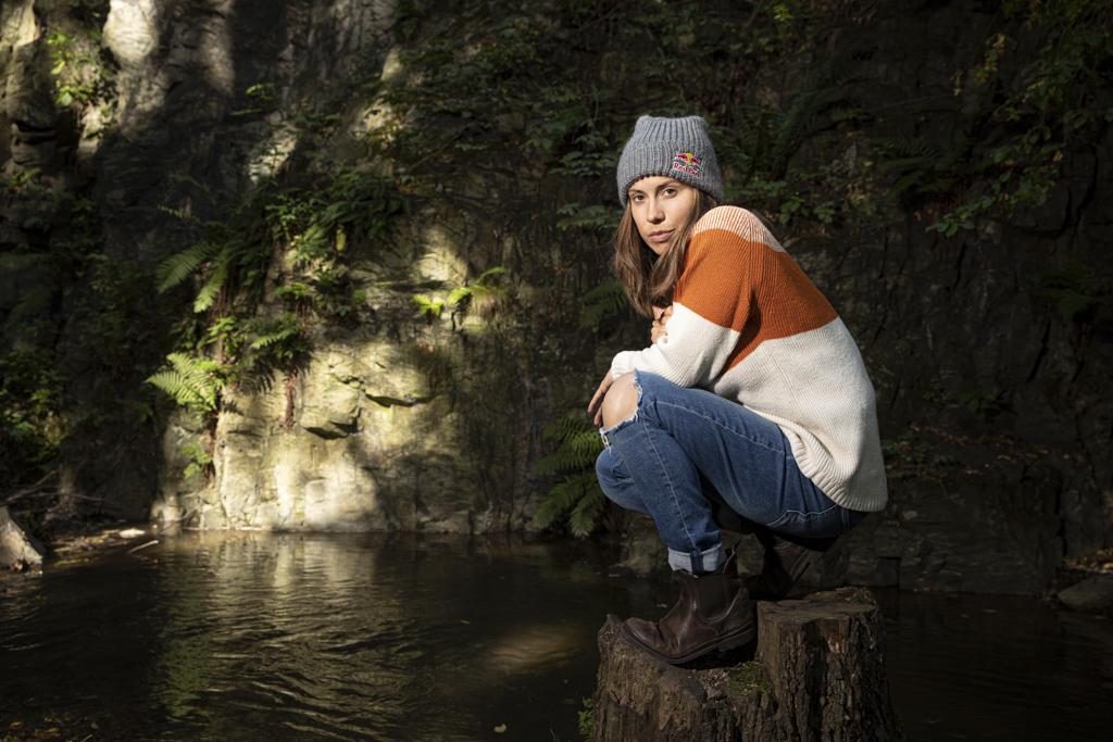 zamyšlená Eva Samková sedí u vody na pařezu