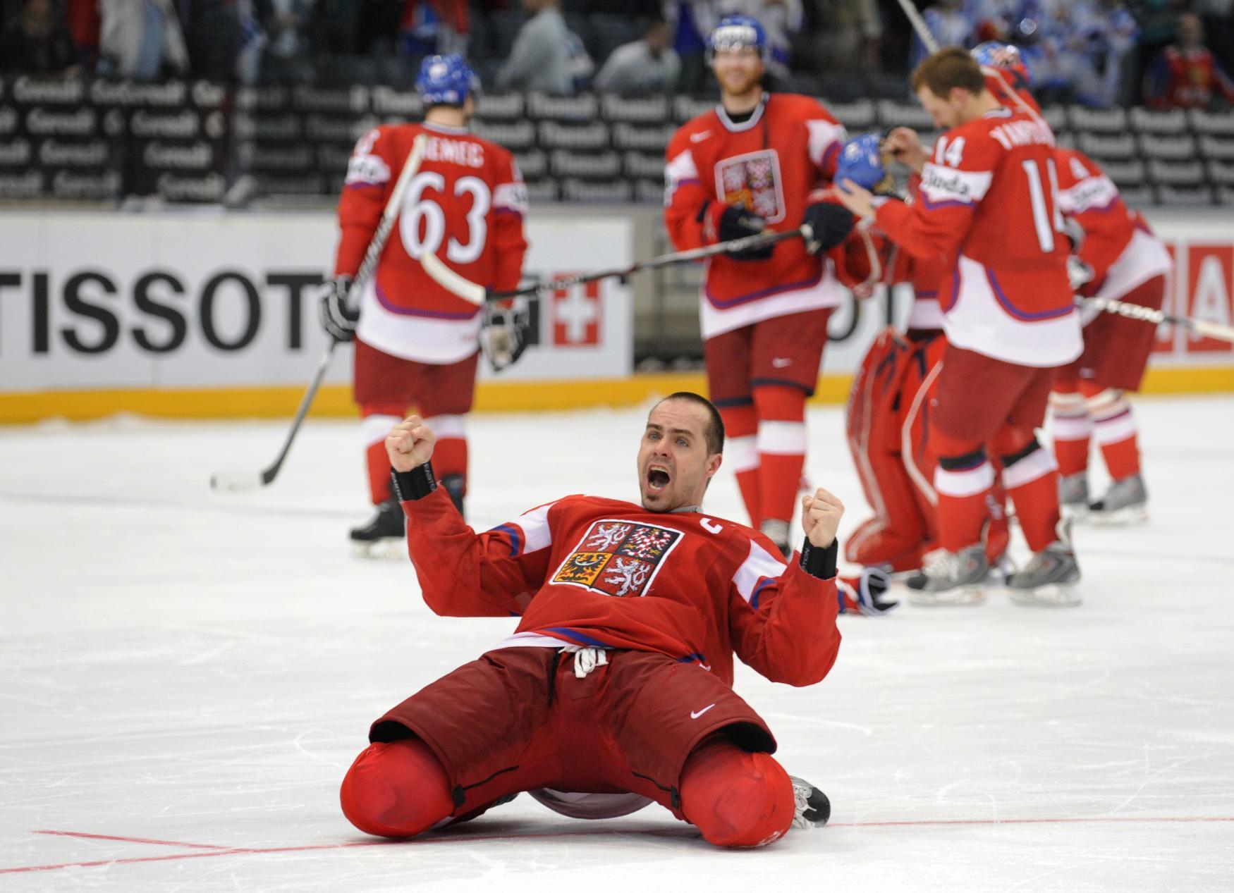 Tomáš Rolinek se raduje na hokejovém zápase na ledě, za ním jeho spoluhráči