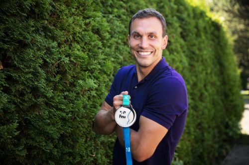 Michal Navrátil  drží v ruce medaili před stromy