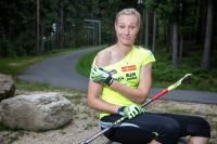 Veronika Zvařičová sedí na kameni u biatlonové trati a ukazuje rameno