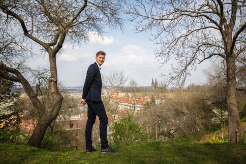 Filip Neusser stojí v saku před výhledem na Prahu