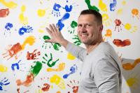 Jan Čaloun přikládá svojí ruku na dětskou malbu rukou