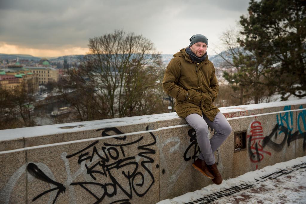 Ondřej Kratěna sedí na pomalované zasněžené zídce.