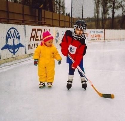 mladá Alena Polenská pozoruje bratra v hokejové výstroji na ledě
