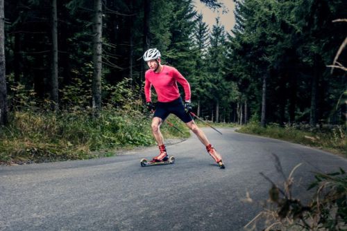 Lukáš Bauer projíždí přírodou na lyžích s kolečky.