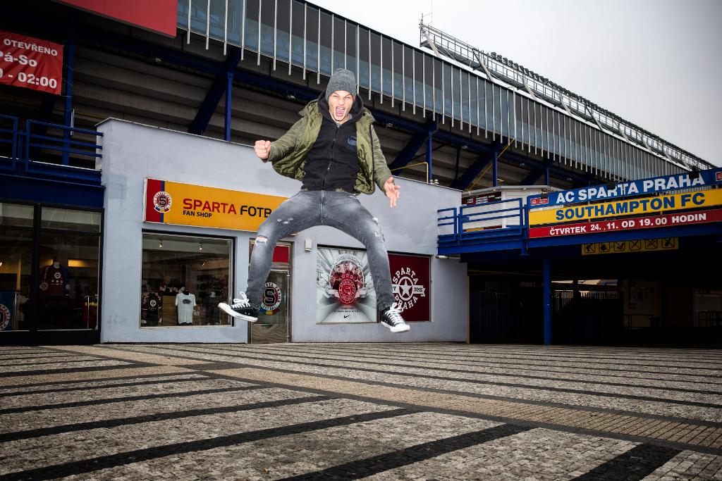 Matěj Pulkrab skáče radostí před sparťanským fotbalovým stadionem.
