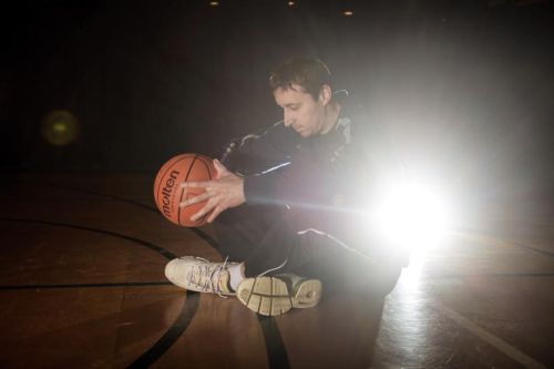 Pavel Miloš sedí na palubovce s basketbalovým míčem  v ruce.