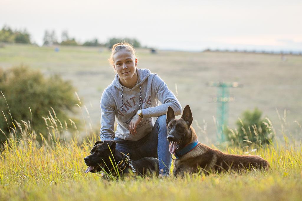 Tereza Bledá sedí v trávě na louce s dvěma psy 