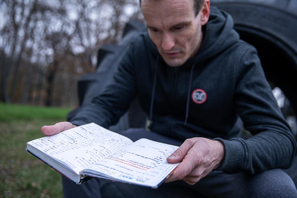 Ondřej Kašpárek sedí před velkou pneumatikou a kouká do zápisníku