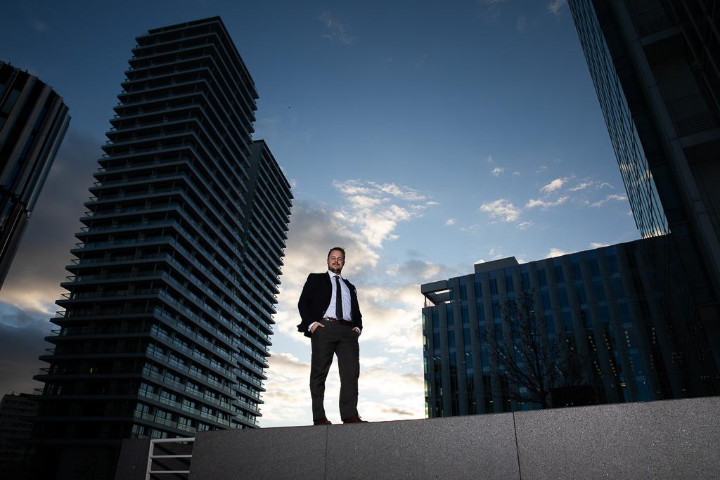 Adam Kotrba pózuje fotografce, v pozadí jsou mrakodrapy