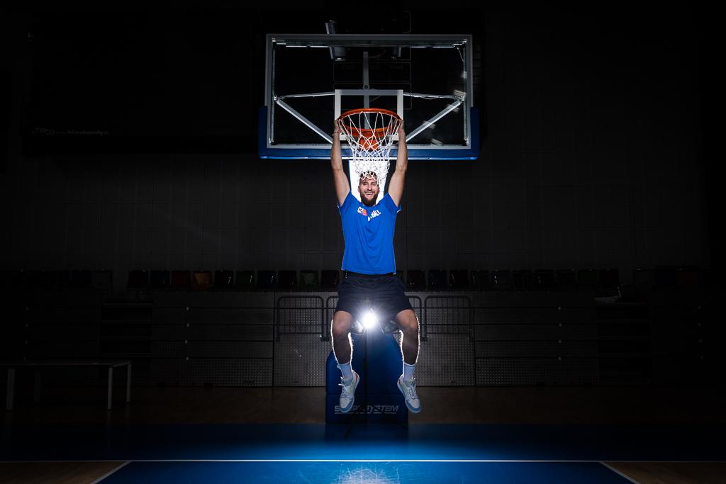 Martin Kříž je ve vzduchu zavěšení za basketbalový koš.