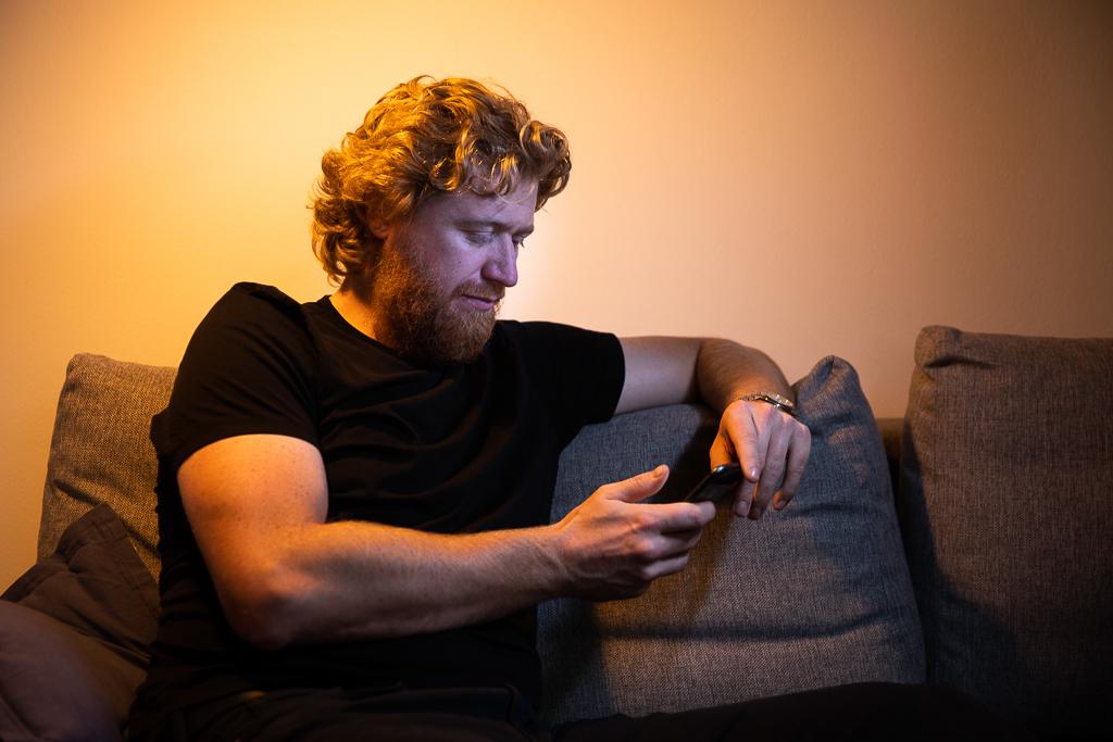 Jakub Voráček sedí na gauči a dívá se do telefonu