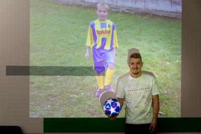 Michal Sadílek s fotbalovým míčem před projektorem se svou fotografií, když byl malý