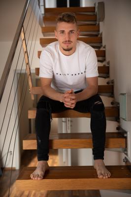 Michal Sadílek sedí na schodech v domě