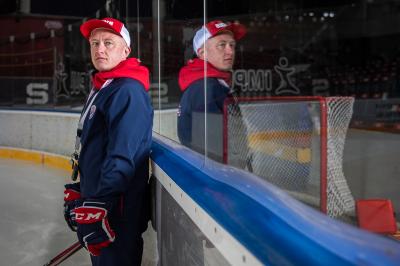 Mikael Pančák stojí na ledě s hokejovými rukavicemi a hokejkou vedle mantinelu, v drazu je hokejová branka