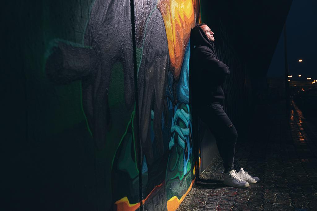 Jan Veleba se opírá o zed' s graffiti se založenýma rukama