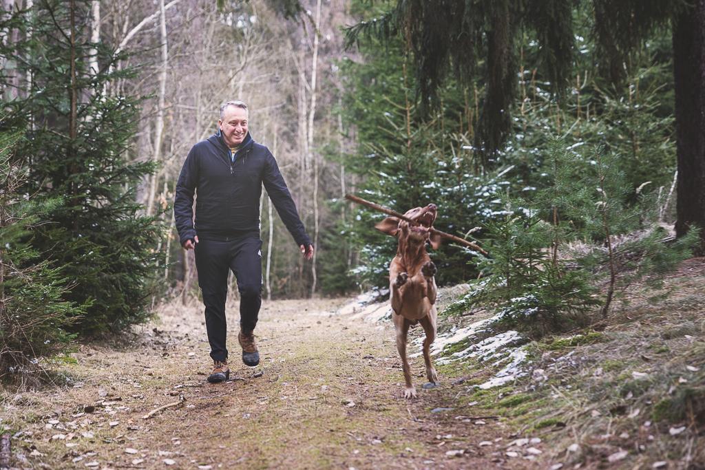 Václav Krejčík se psem, který má v puse klacek, jsou v lese