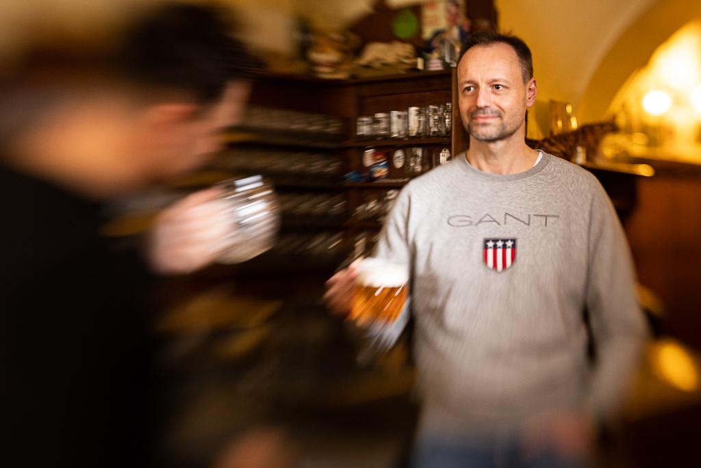 Petr Míka stojí v hospodě a drží půlitr s pivem