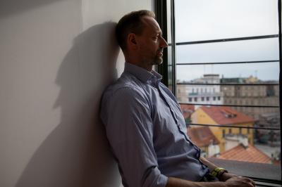 Petr Míka sedí u okna, má výhled na město