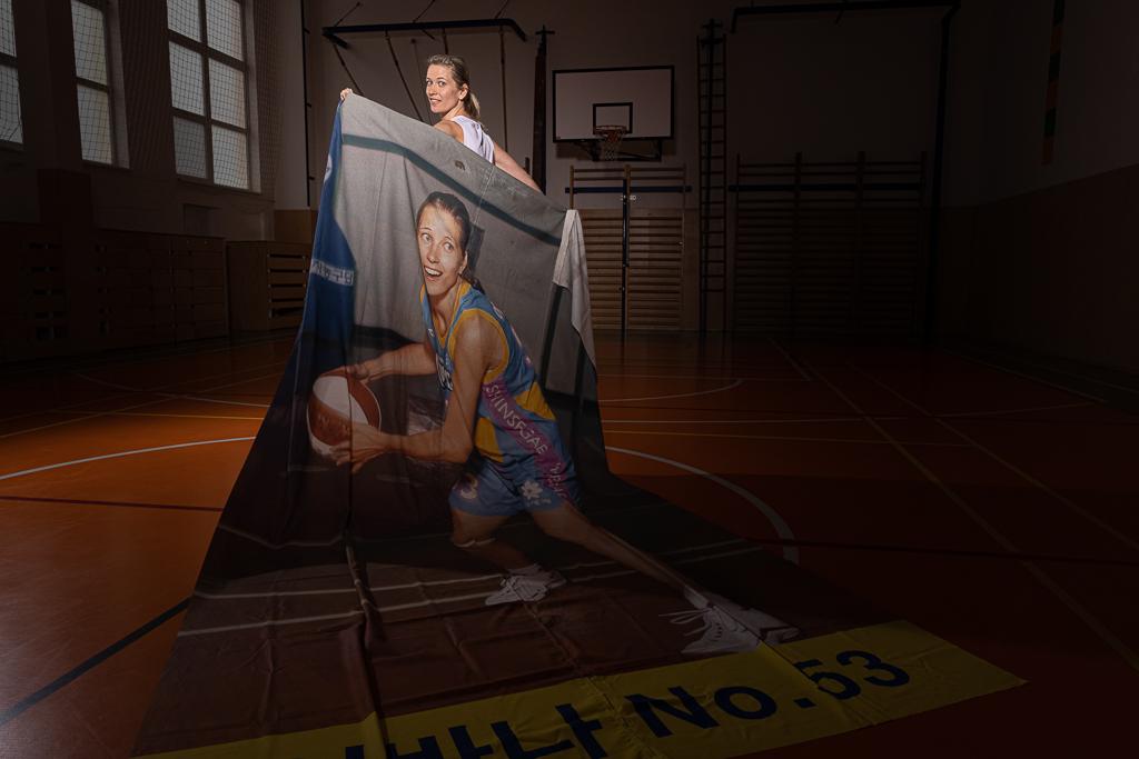 Ivana Večeřová v tělocvičně s plakátem se sebou jak hraje basketal