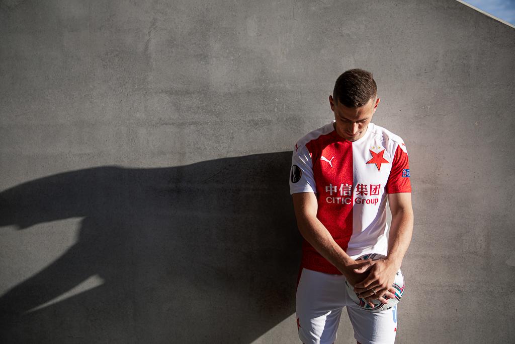 Tomáš Holeš stojí u zdi ve fotbalovém dresu Slavie, drží v rukou míč