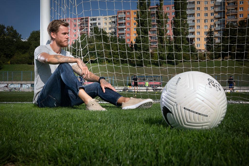 Marek Střeštík sedí na fotbalovém trávníku, v popředí je fotbalový míč.