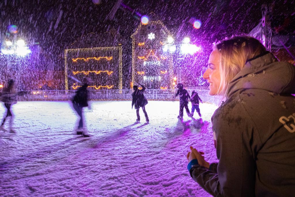 Markéta Jeřábková stojí u ledu na náměstí, kde lidé bruslí, velmi hustě sněží