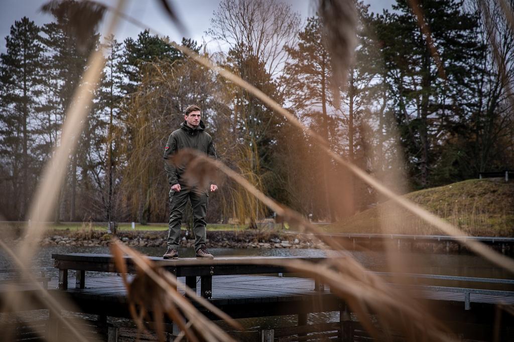 Pohled na Davida Dvořáka přes rákosí, jak stojí u rybníka.