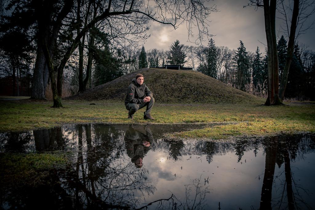 David Dvořák v podřepu u rybníka, u kterého vyrůstal.