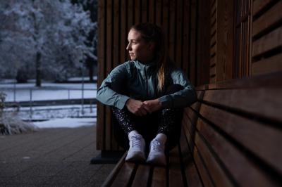 Aneta Grabmüllerová sedí na dřevěné lavičce, venku je sníh