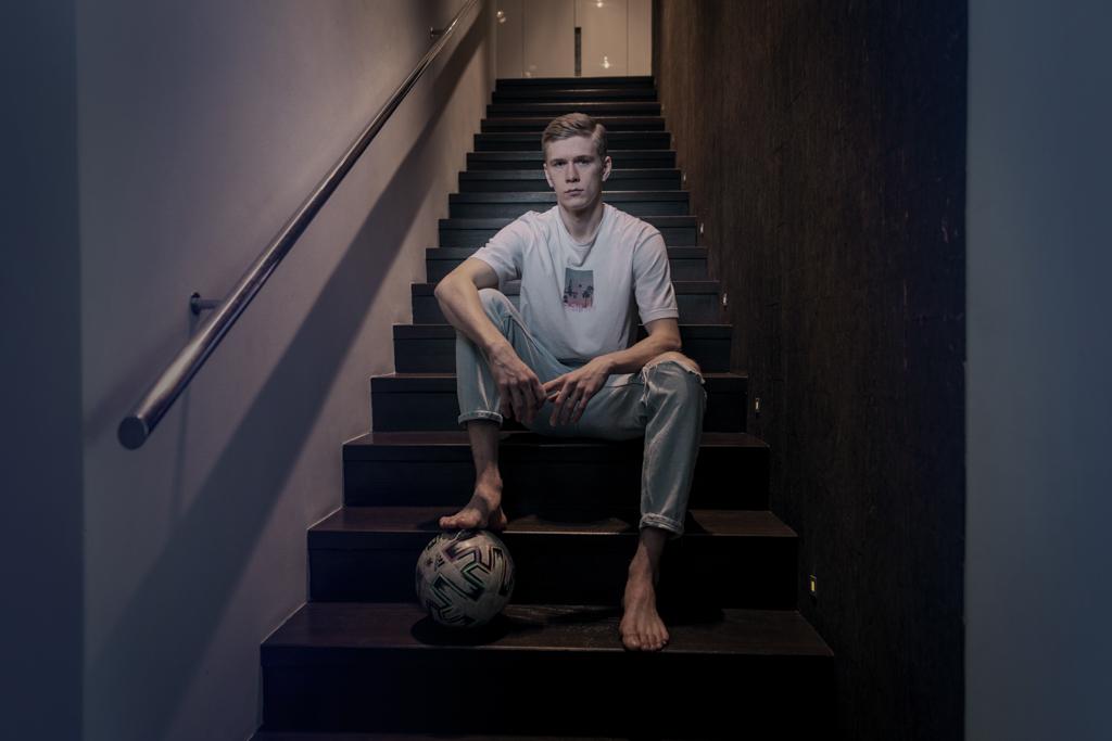Jegor Cykalo sedí na schodech, pod nohou má fotbalový míč.