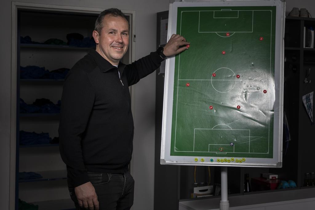Tomáš Galásek stojí u tabulky s fotbalovým hřištěm, ukazuje taktiku