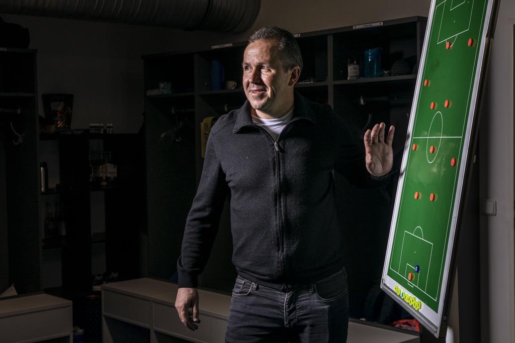 Tomáš Galásek stojí v šatně u tabulky s fotbalovým hřištěm, ukazuje taktiku