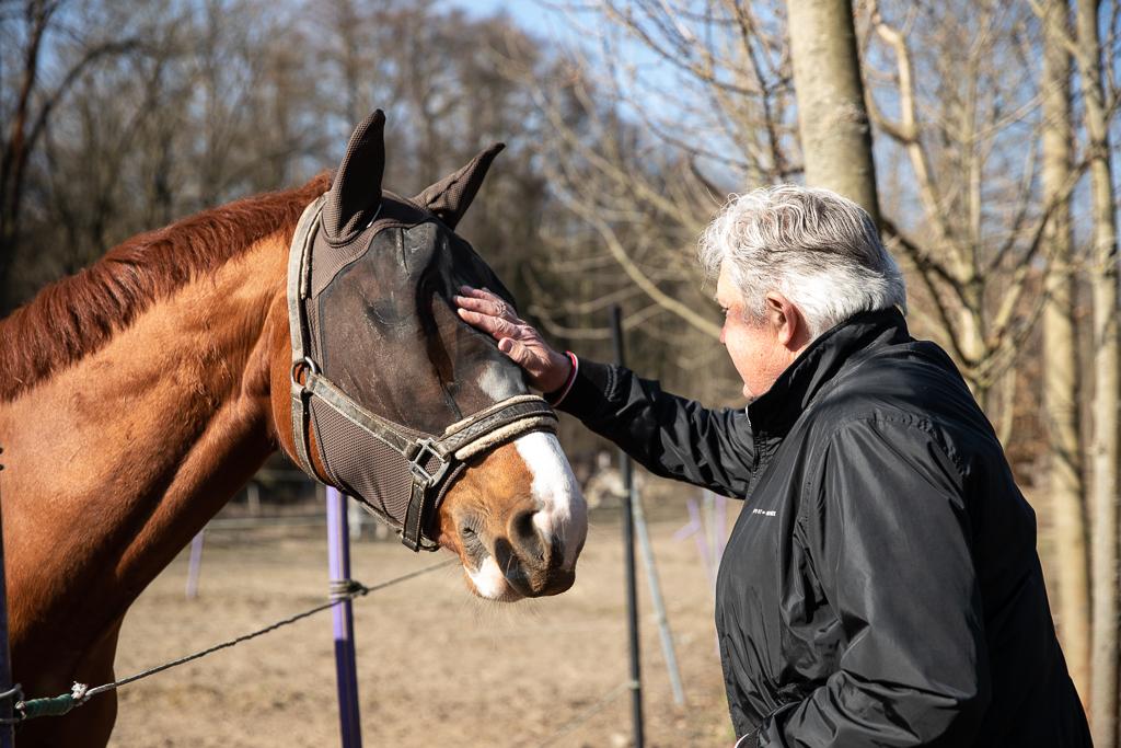 Jiří Pecháček hladí koně po obličeji v přírodě