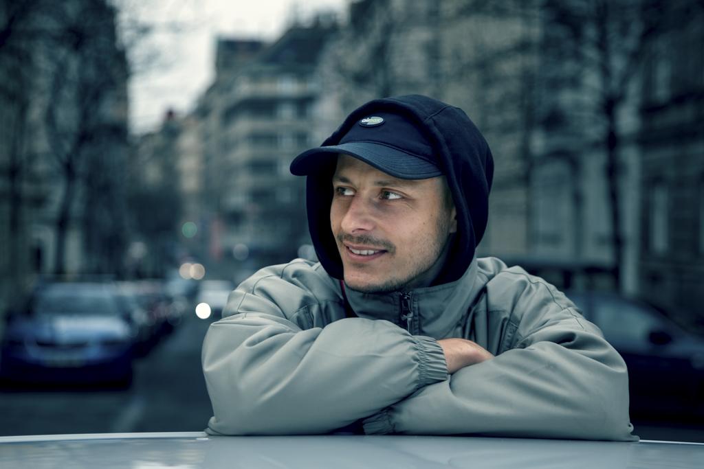 Tomáš Kučera se dívá do strany opřený o auto.