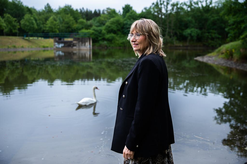 Alice Roubalová se u rybníka ohlíží přes rameno, za ní pluje labuť.