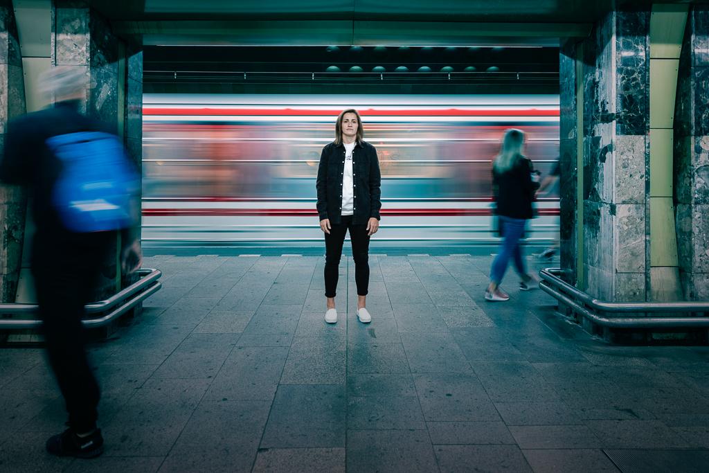 Tereza Vytlačilová stojí na nástupišti a za ní projíždí metro