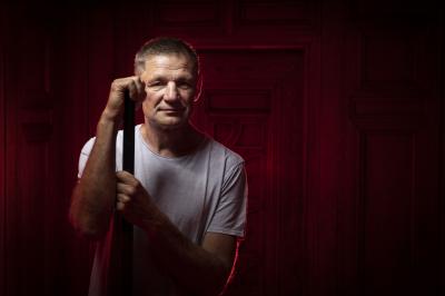 František Musil s hokejkouo před zdí nasvícenou červenně
